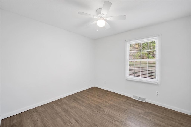spare room featuring visible vents, baseboards, ceiling fan, and wood finished floors