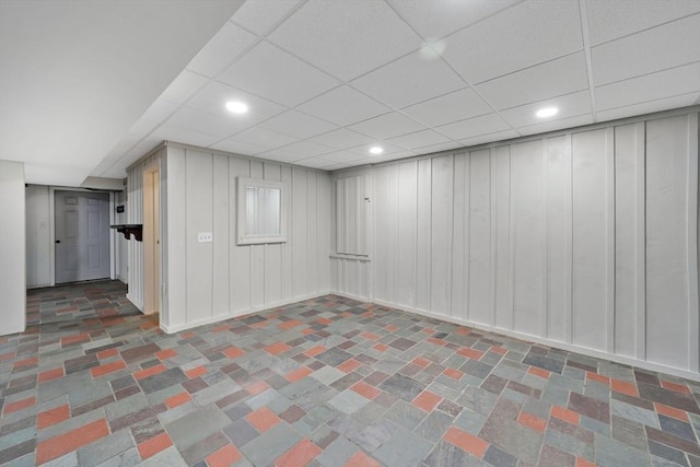 finished basement featuring a decorative wall, recessed lighting, and a paneled ceiling