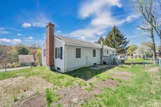 back of house with a lawn, a wooden deck, fence, and a chimney