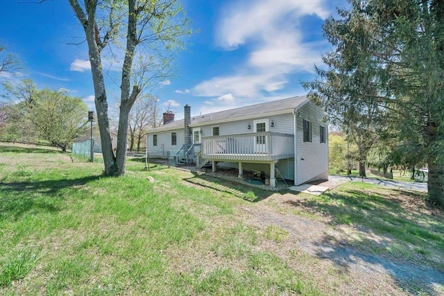 back of house featuring a lawn, a chimney, and a deck