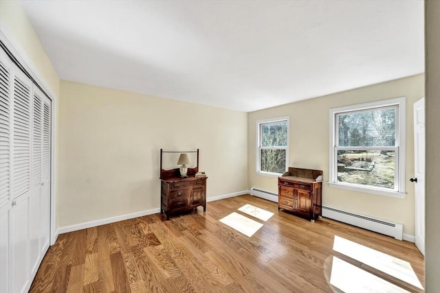 living area featuring wood finished floors, baseboards, and baseboard heating