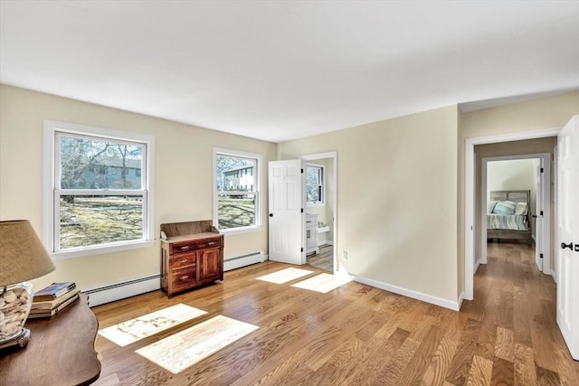 sitting room with a baseboard heating unit, baseboards, baseboard heating, and light wood-style flooring