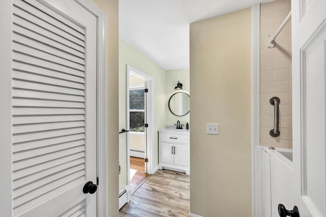 bathroom featuring a shower, a baseboard radiator, wood finished floors, and vanity