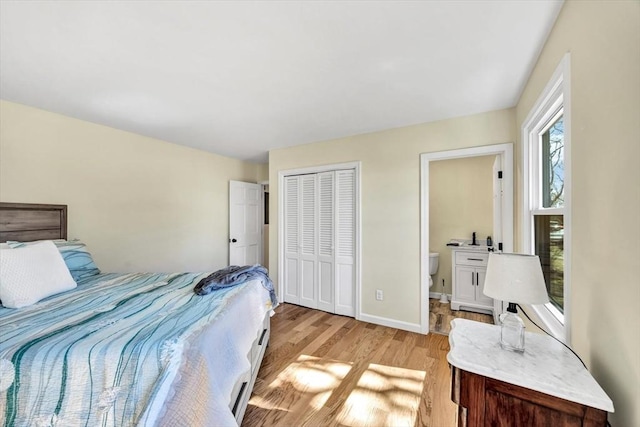 bedroom with a closet, baseboards, light wood-style floors, and ensuite bathroom