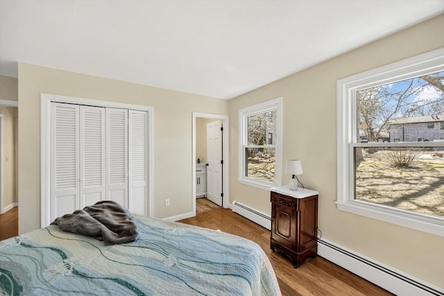 bedroom featuring a closet, multiple windows, and baseboard heating