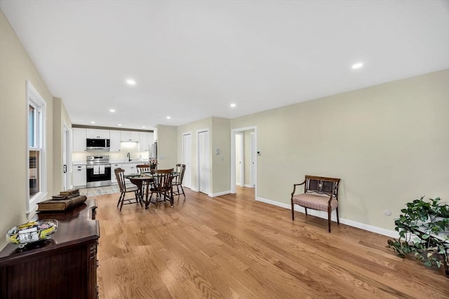 dining room with light wood-style flooring, recessed lighting, and baseboards