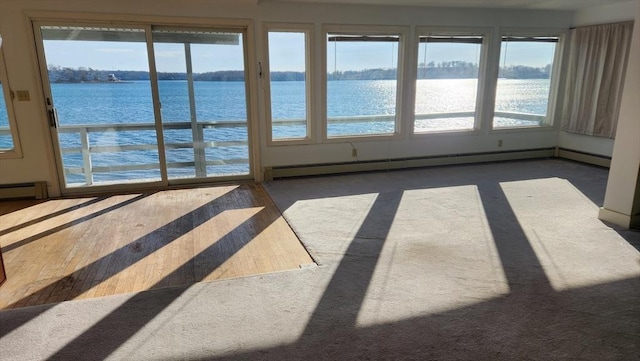 unfurnished sunroom featuring a water view and a baseboard radiator