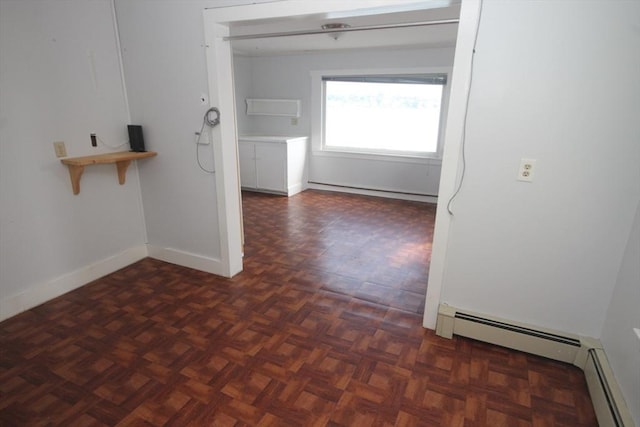 corridor with dark parquet floors and a baseboard heating unit