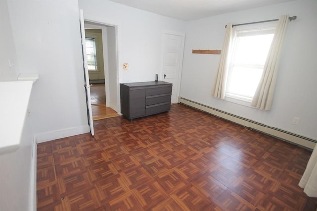 spare room featuring dark parquet flooring and a baseboard heating unit