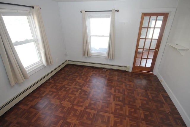 empty room with dark parquet flooring, a baseboard radiator, and plenty of natural light