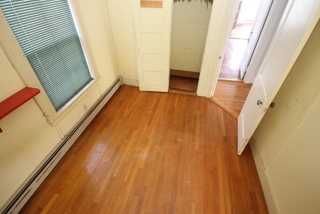 unfurnished bedroom featuring hardwood / wood-style floors, a closet, and a baseboard radiator