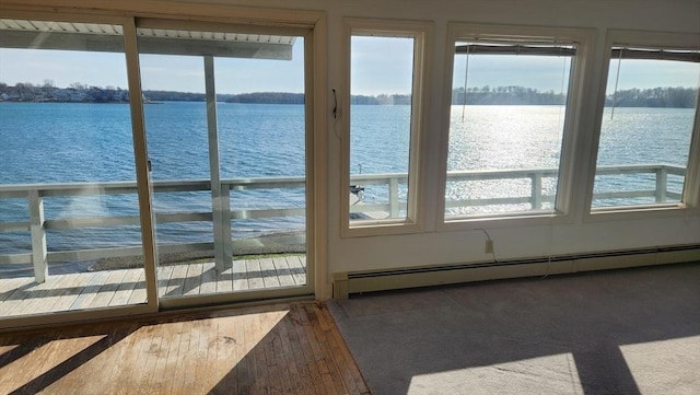 doorway featuring a healthy amount of sunlight, a water view, and a baseboard heating unit