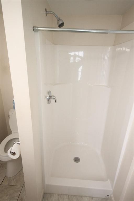 bathroom featuring tile patterned floors, toilet, and a shower