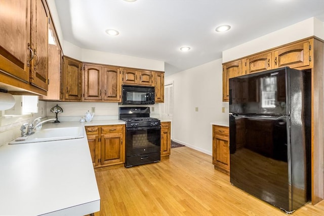 53 Wingfoot Dr, Barnstable, MA 02675 - kitchen with black appliances, a sink, light countertops, light wood-style flooring, and brown cabinetry
