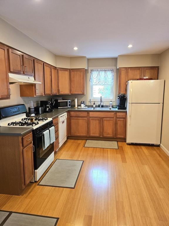 94 Barton St Unit 3, Pawtucket, RI 02860 - kitchen with white appliances, under cabinet range hood, a sink, brown cabinets, and recessed lighting