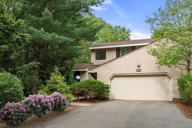 204 Allandale Rd Unit A, Boston, MA 02467 - view of front of house with stucco siding, driveway, an attached garage, and roof with shingles