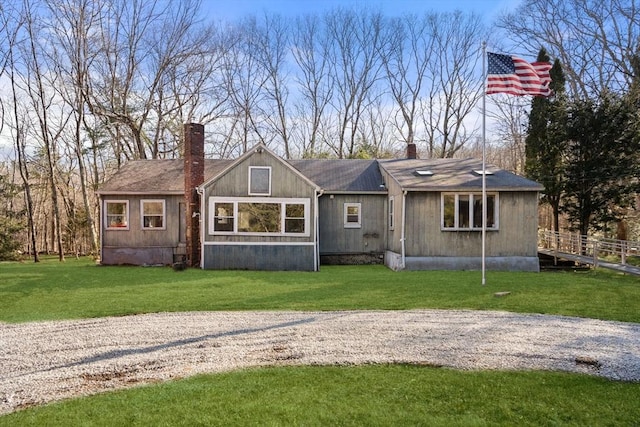 back of house featuring a lawn and a chimney