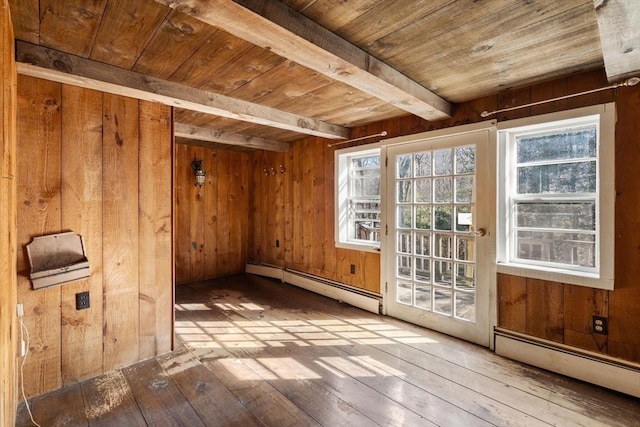 interior space with wooden walls, a baseboard heating unit, and hardwood / wood-style floors