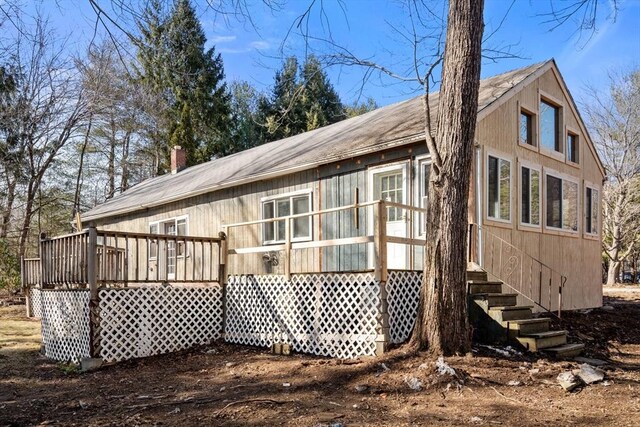 back of property with a wooden deck and a chimney