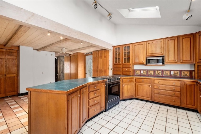 kitchen featuring stainless steel microwave, brown cabinetry, black gas range oven, and a peninsula