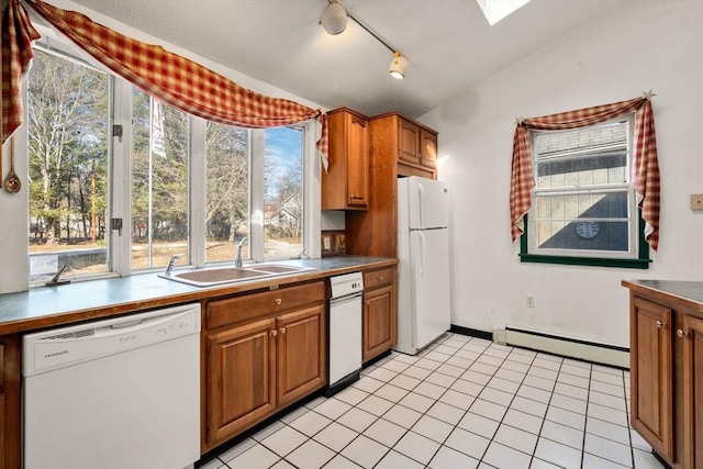 kitchen featuring white appliances, a sink, lofted ceiling with skylight, brown cabinets, and baseboard heating