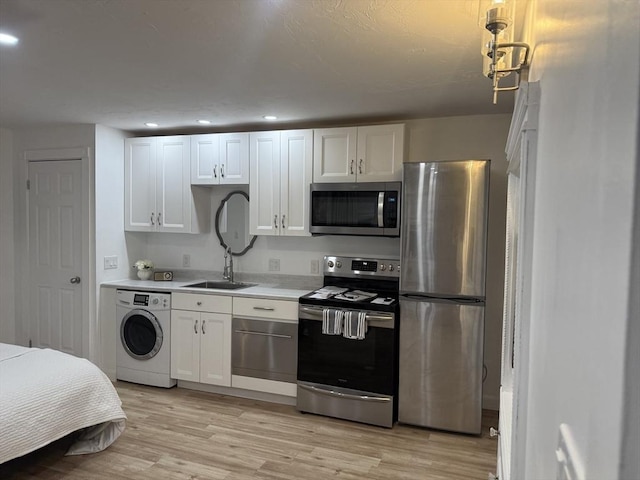 kitchen with stainless steel appliances, light countertops, white cabinets, a sink, and washer / dryer