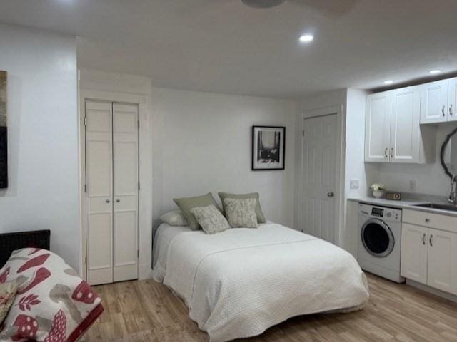 bedroom featuring washer / dryer, light wood-style flooring, a sink, multiple closets, and recessed lighting