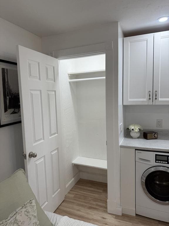 laundry room featuring washer / clothes dryer, light wood-type flooring, and cabinet space