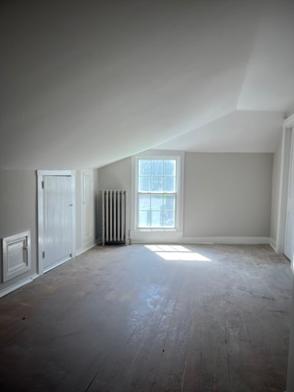 additional living space with lofted ceiling, radiator heating unit, and hardwood / wood-style flooring