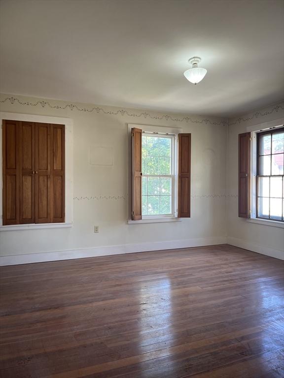 spare room with dark wood-type flooring and a healthy amount of sunlight