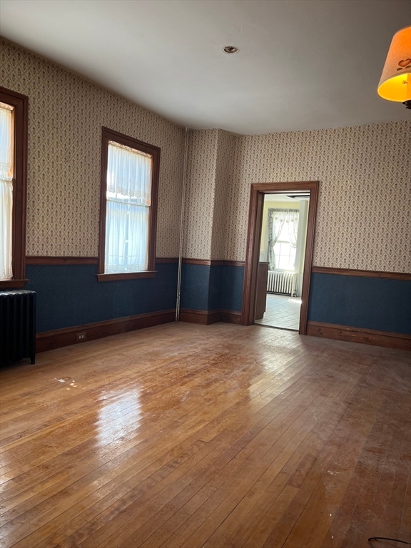 empty room featuring hardwood / wood-style floors and radiator heating unit