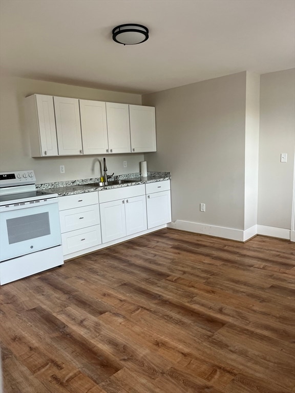 kitchen featuring dark hardwood / wood-style floors, white electric range, white cabinets, sink, and stone counters