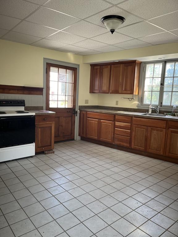 kitchen with a paneled ceiling, light tile patterned floors, sink, and white electric range oven