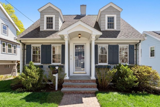 cape cod home featuring roof with shingles and a chimney