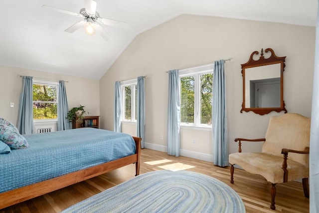 bedroom featuring a ceiling fan, baseboards, vaulted ceiling, and light wood-style flooring