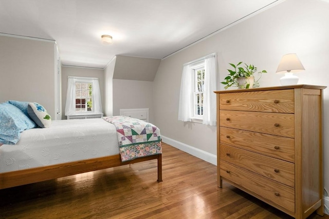bedroom with baseboards, vaulted ceiling, and wood finished floors