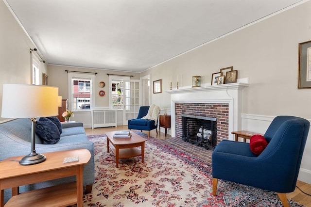 living room with crown molding, radiator, a fireplace, and wood finished floors