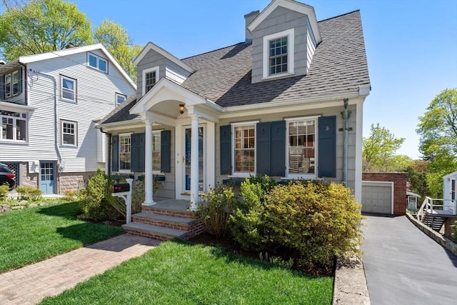 view of front of home with roof with shingles, a garage, a porch, and a front yard
