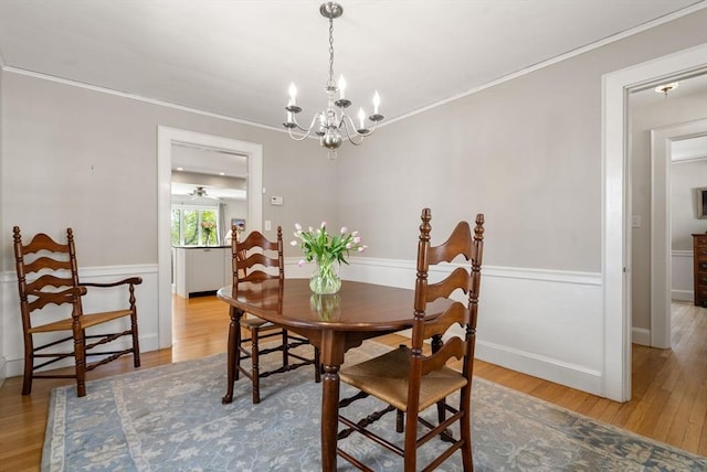 dining space featuring ornamental molding, wood finished floors, and a notable chandelier