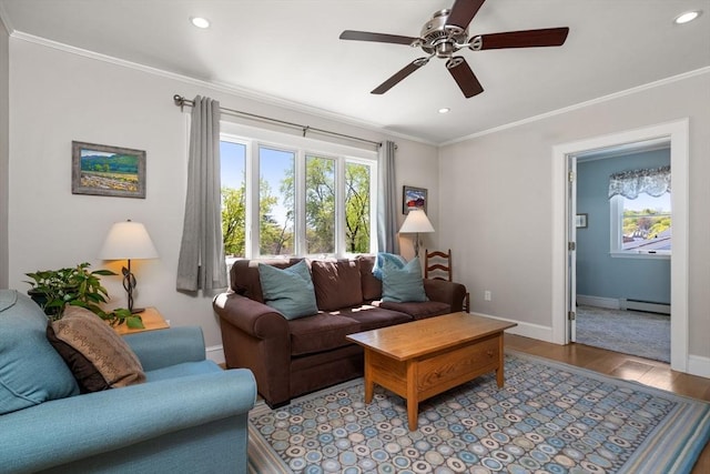 living area featuring a ceiling fan, baseboard heating, wood finished floors, baseboards, and ornamental molding