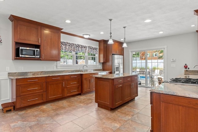 2 Dana Dr, Groveland, MA 01834 - kitchen featuring appliances with stainless steel finishes, a sink, a center island, brown cabinets, and light stone counters