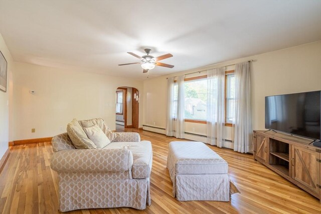 60 Highland Ave, Leominster, MA 01453 - living area with arched walkways, ceiling fan, light wood-style floors, baseboards, and a baseboard heating unit