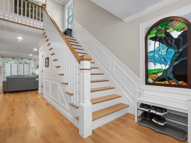 83 Boynton St, Waltham, MA 02453 - stairs featuring a decorative wall, ornamental molding, wood finished floors, healthy amount of natural light, and a wainscoted wall