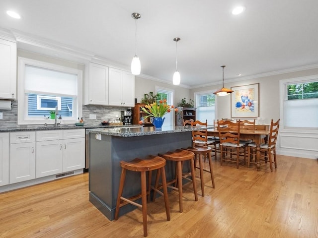 83 Boynton St, Waltham, MA 02453 - kitchen featuring a sink, healthy amount of natural light, a center island, decorative backsplash, and ornamental molding
