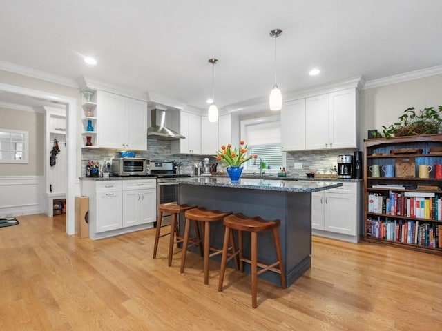 83 Boynton St, Waltham, MA 02453 - kitchen featuring electric stove, wall chimney range hood, light wood-style floors, white cabinetry, and ornamental molding