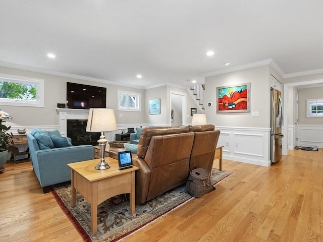 83 Boynton St, Waltham, MA 02453 - living room with healthy amount of natural light, ornamental molding, stairway, light wood-style floors, and wainscoting