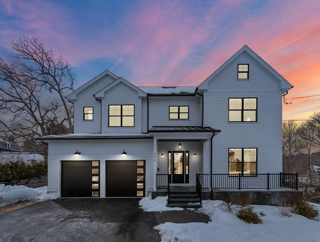 modern farmhouse style home featuring driveway, a garage, metal roof, a standing seam roof, and a porch