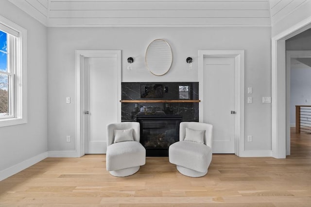 sitting room featuring a fireplace, baseboards, and wood finished floors