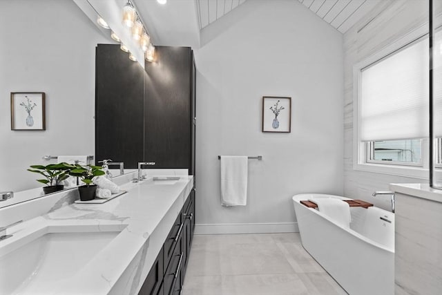 bathroom with lofted ceiling, a freestanding bath, double vanity, and a sink