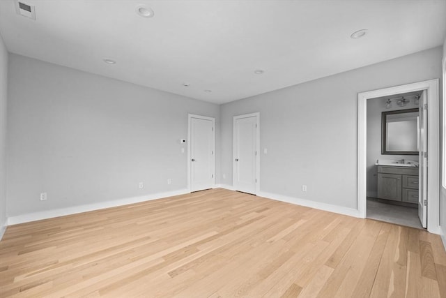 interior space with baseboards, visible vents, light wood-style floors, a sink, and recessed lighting